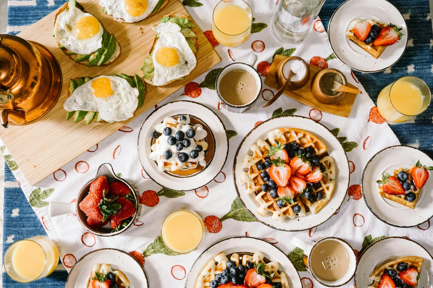 Ontbijttafel met wafels, eieren, fruit en glazen sap.