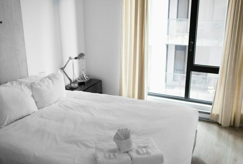 Hotelkamer met een wit opgemaakt bed naast een raam.