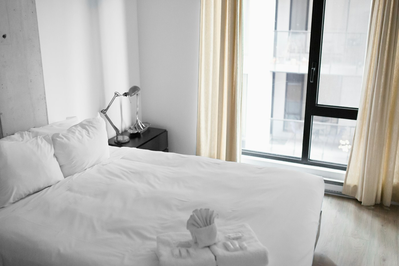Hotelkamer met een wit opgemaakt bed naast een raam.