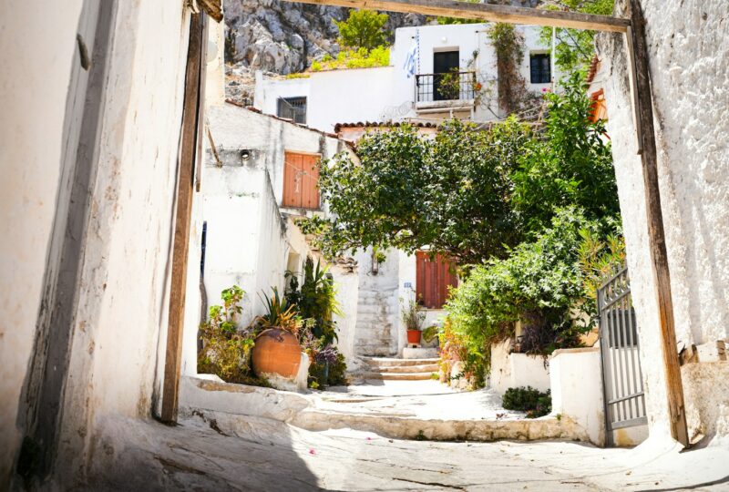 Een smal stenen straatje tussen witte huizen en groen in Anafiotika, Athene.