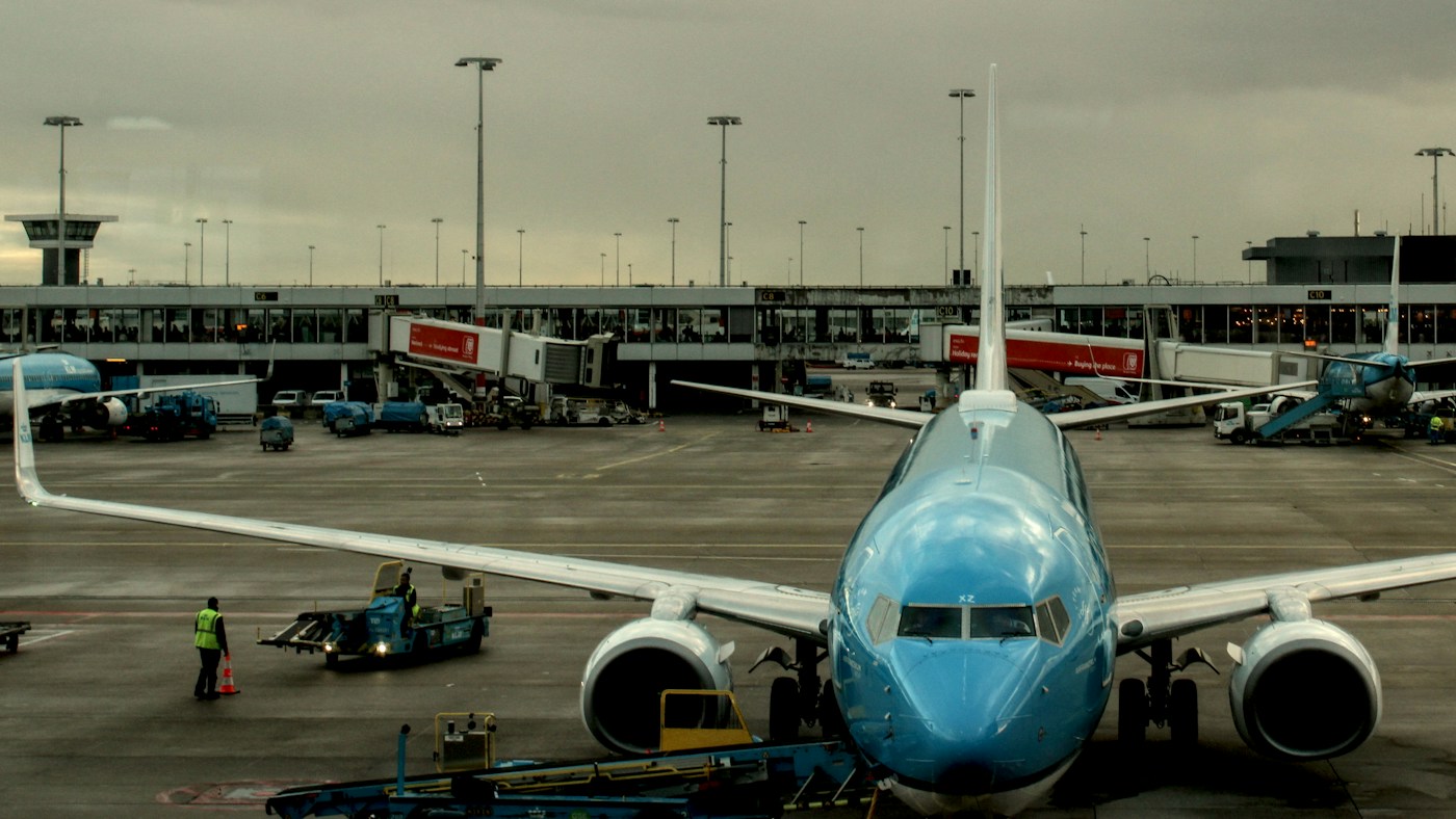 Vliegtuig met een passagiersbrug aan een gate op Schiphol.