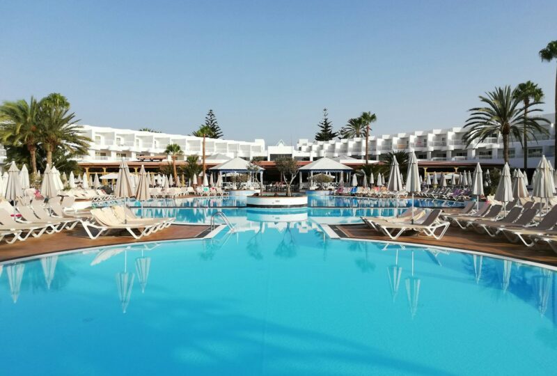 Ligstoelen en palmbomen langs een buitenzwembad bij een resort op Lanzarote.